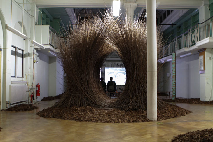 Visitors watching A Natural History of Nest Building (2017), seen through Untitled (Bower) (2017).