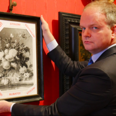 Uffizi director Eike Schmidt with a framed photograph of 'Vase of Flowers' and the word 'stolen' in Italian, English and German. Photo: @UffiziGalleries via Twitter