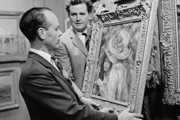 An art adviser, Graham Reid, examines a painting (Les Deux Soeurs) by Pierre-Auguste Renoir before its auction at Sotheby’s in London in 1963.