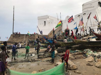 Fishermen in front of Cape Coast Castle, Ghana, with a staircase on the left leading up to a ‘Door of No Return’.
