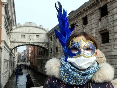 A tourist in Venice on 24 February 2020, wearing a protective face-mask and a Carnival mask.